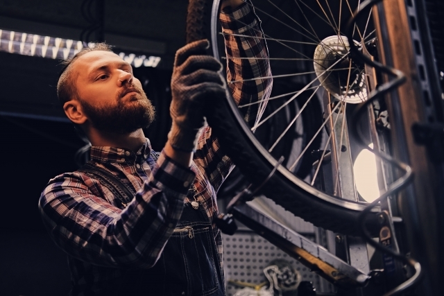 bearded-mechanic-doing-bicycle-wheel-service-manual-in-workshop
